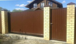 Забор с откатными воротами с автоматикой и кирпичными столбами.<br />Высота 2м.