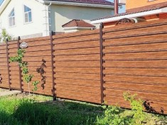 Горизонтальный забор из двухстороннего металлического штакетника под темное дерево в секциях с установкой