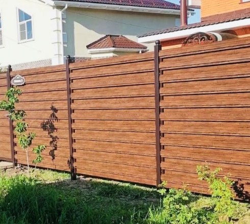 Горизонтальный забор из двухстороннего металлического штакетника под темное дерево в секциях с установкой